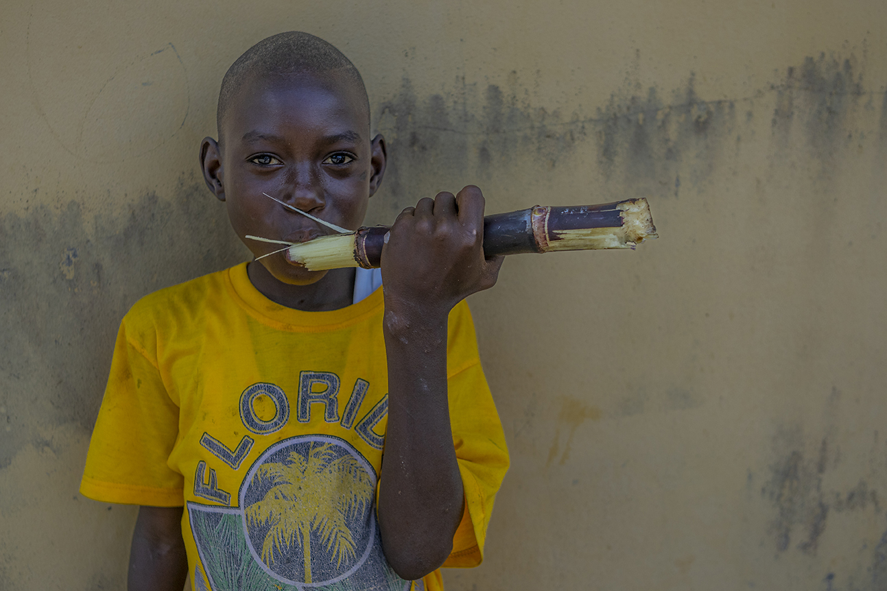A young boy pose with sugarcane 